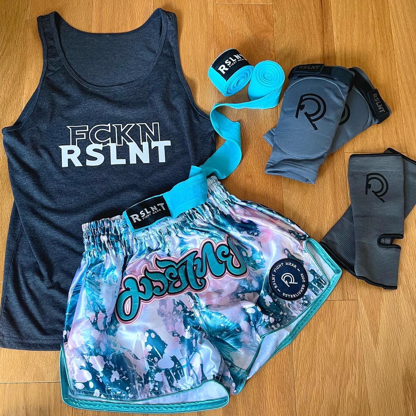 RSLNT apparel and illustrated Muay Thai shorts arranged in a colorful product flat lay.